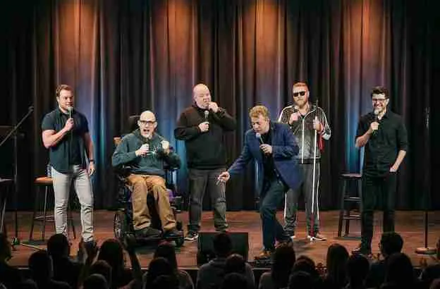 Six comedians perform on stage, engaging the audience with humor and showcasing diversity in comedy.